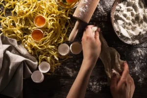 Fresh handmade pasta in Singapore being prepared with flour and eggs on a kitchen counter.
