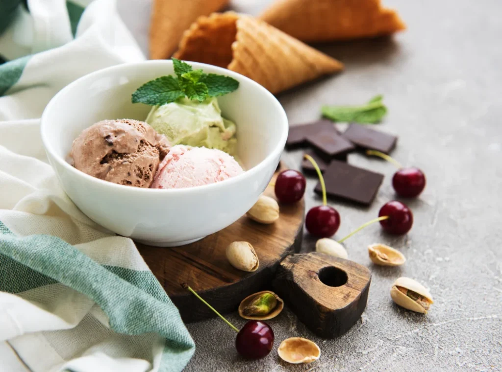 a bowl containing three scoops of green, pink, and brown gelato

