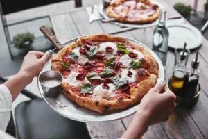 Waitress carrying a plate of Italian pizza in Singapore