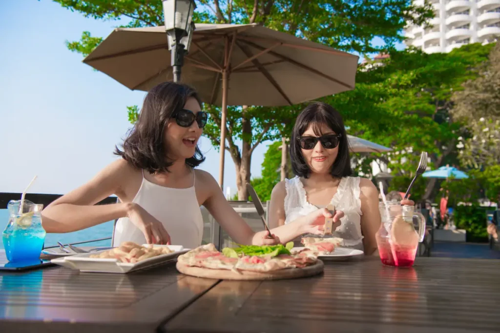 Two Asian women enjoying pizza while alfresco dining in Singapore.