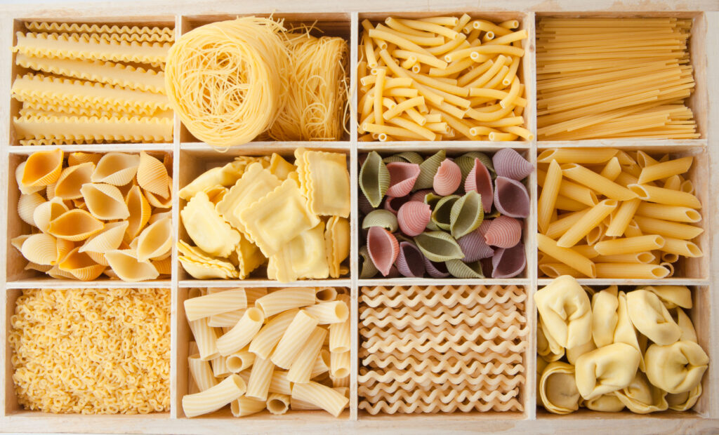 Different handmade pasta shapes on a wooden tray